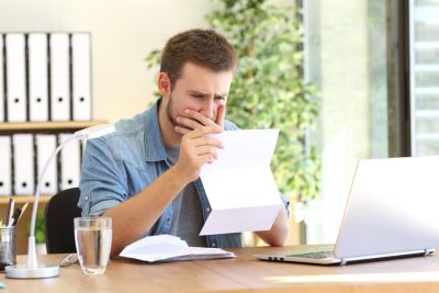 Worried man reading a letter at his desk